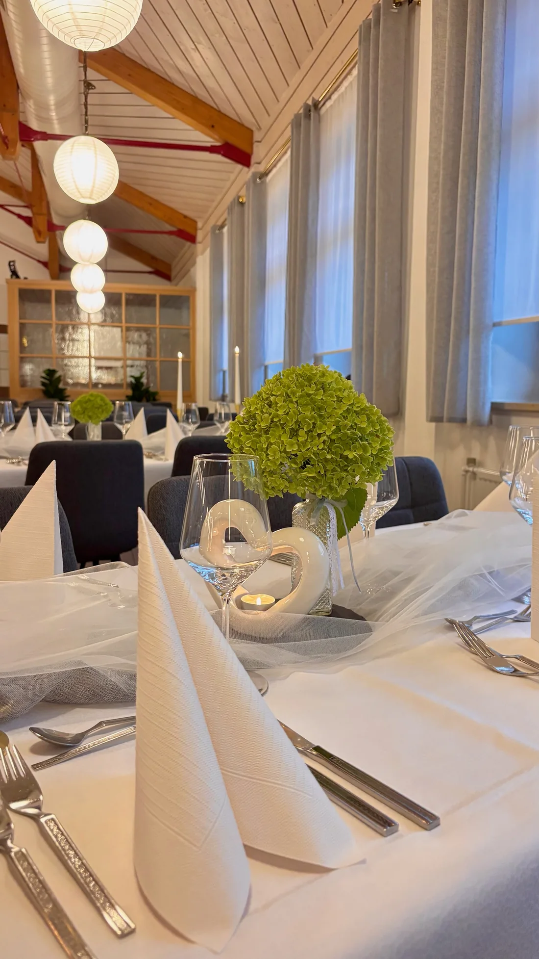 Festlich gedeckter Saal mit Kerzen und Blumenschmuck für eine Hochzeit